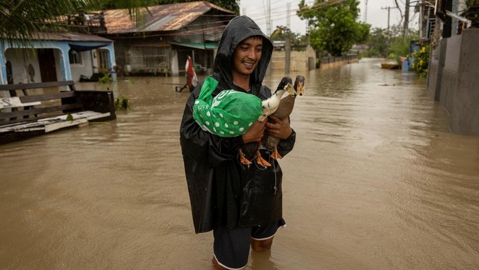 Aktivitas Warga Filipina Dikala Banjir Melanda A man wades through floodwaters with a fishing boat carrying furniture as it rains during Tropical Storm Yagi, locally known as Enteng in Apalit, Pampanga, Philippines, September 5, 2024. REUTERS/Eloisa Lopez