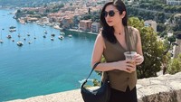 Seperti momennya saat liburan di Nice, Perancis ini. Ia berpose memegang es kopi dengan pemandangan laut biru. Foto: Instagram @amandarigby6