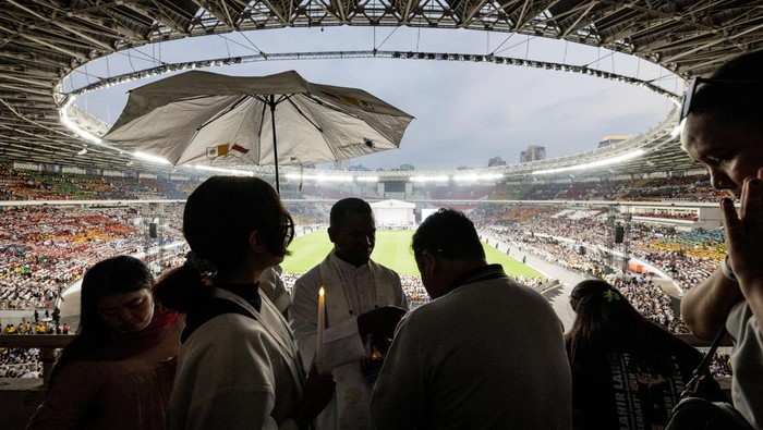 Momen Paus Fransiskus Pimpin Misa Akbar di GBK A priest gives Holy Communion to the faithful during a holy mass led by Pope Francis at the Gelora Bung Karno Stadium in Jakarta on September 5, 2024. YASUYOSHI CHIBA/Pool via REUTERS