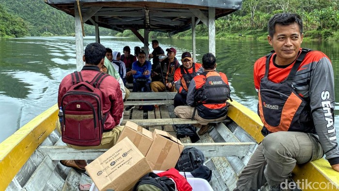 Relawan Sehati menembus arus sungai untuk menuju ke lokasi permukiman di Cibitung