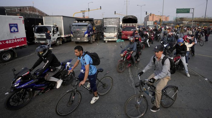 Commuters pedal and walk due to a lack of transport caused by truckers blocking streets in protest of an increase in diesel prices, in Bogotá, Colombia, Wednesday, Sept. 4, 2024. (AP Photo/Fernando Vergara)