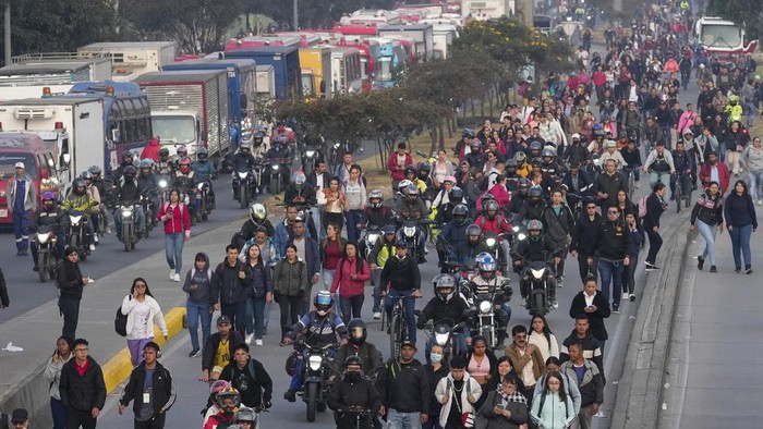 Commuters pedal and walk due to a lack of transport caused by truckers blocking streets in protest of an increase in diesel prices, in Bogotá, Colombia, Wednesday, Sept. 4, 2024. (AP Photo/Fernando Vergara)