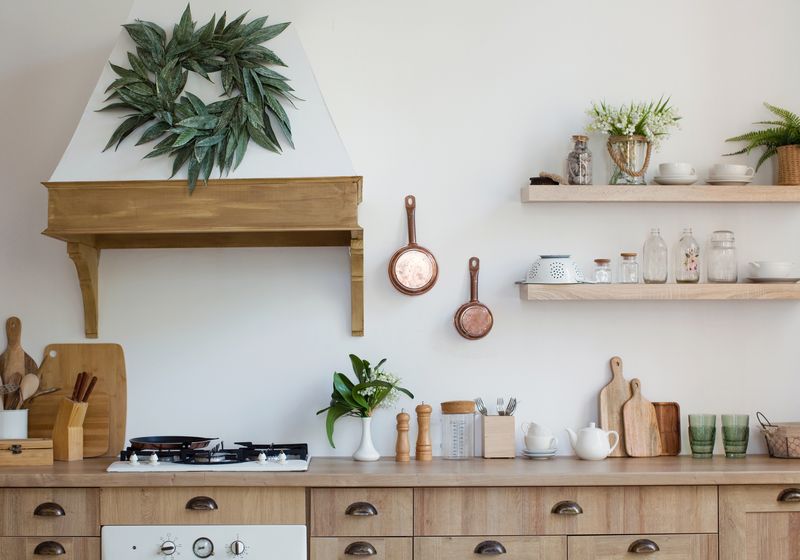 Light wooden kitchen interior with kitchen utensils on the shelves and on the wall. Beautiful kitchen interior design