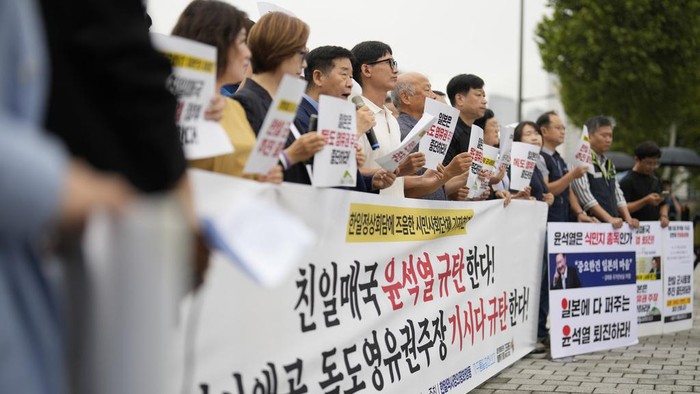 Aksi Protes Menentang PM Jepang Fumio Kishida Berkunjung ke Korsel A protester shouts slogan with a sign reading
