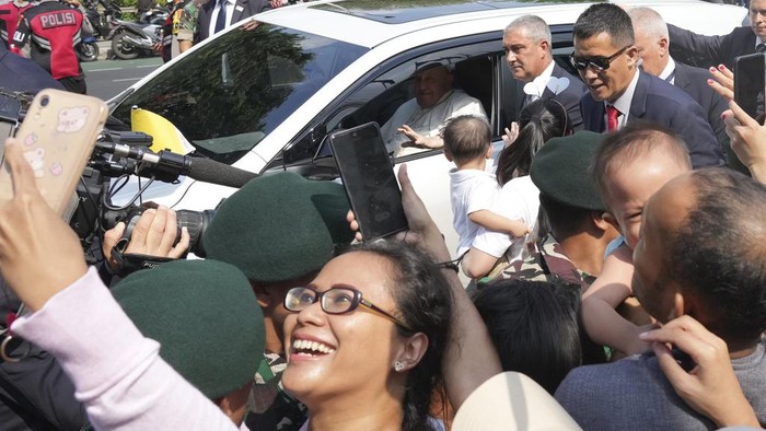 Pope Francis waves from inside a car as he departs Vatican Embassy for an airport, in Jakarta, Indonesia, Friday, Sept. 6, 2024. (AP Photo/Achmad Ibrahim)