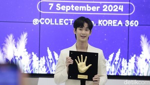Kim Soo Hyun hadir mengenakan busana hitam-hitam dengan outer putih.