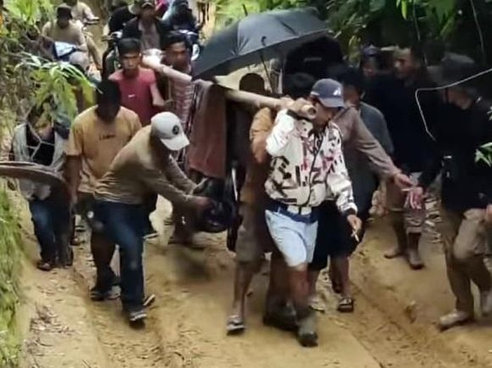 Bidan yang jatuh sakit di Polman ditandu warga karena akses jalan rusak.