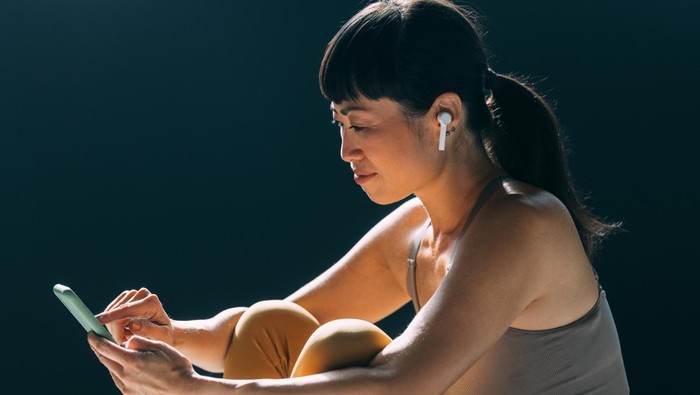 Wanita sedang berolahraga sambil mendengarkan musik lewat TWS