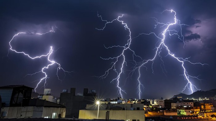 A night sky and flashes of lightning in a small city