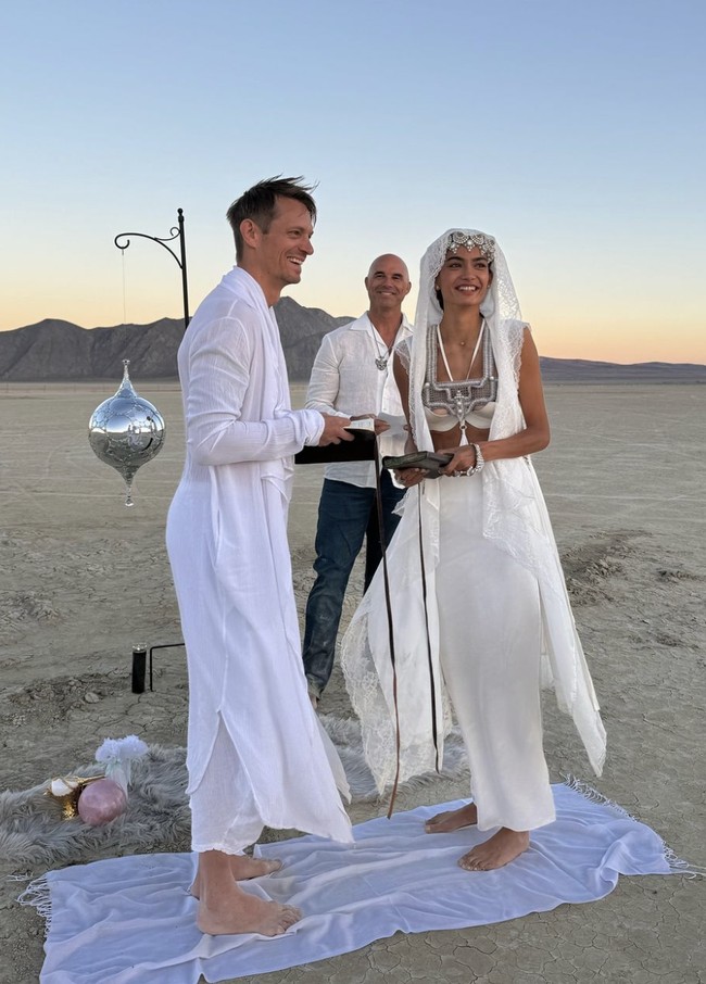 Pasangan ini melangsungkan upacara pernikahan yang intim dan sederhana, dengan pemandangan gurun yang membentang luas sebagai latar belakang. Keduanya menikah dalam suasana yang penuh keunikan dan estetika khas Burning Man. Foto: dok. Instagram @kellygale