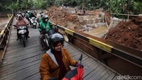 Warga melintas di jembatan darurat yang berada di samping proyek perbaikan jembatan.