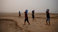 Warga membawa galon air di Sungai Madeira yang mengering di Humaita, negara bagian Amazonas, Brasil, Sabtu (8/9/2024).  