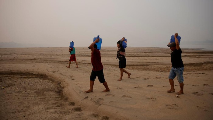 River dwellers fill a tank of water on the sandbanks of the Madeira river to bring to the isolated region of Paraizinho community, during the worst drought of the river in history, Humaita, Amazonas state, Brazil September 8, 2024. REUTERS/Bruno Kelly