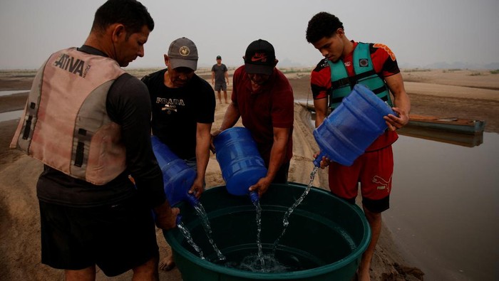 Perjuangan Mendapat Air Bersih Saat Sungai Amazon Mengering Parah River dwellers fill a tank of water on the sandbanks of the Madeira river to bring to the isolated region of Paraizinho community, during the worst drought of the river in history, Humaita, Amazonas state, Brazil September 8, 2024. REUTERS/Bruno Kelly