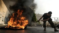 Salah satu anggota memindahkan ban yang dibakar ke tengah jalan.  