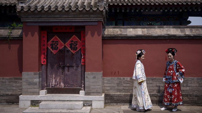 Chinese girls dressed in Qing Dynasty attire take pictures outside the Drum Tower at Gulou East Street in Beijing, China, Tuesday, July 16, 2024. (AP Photo/Vincent Thian)