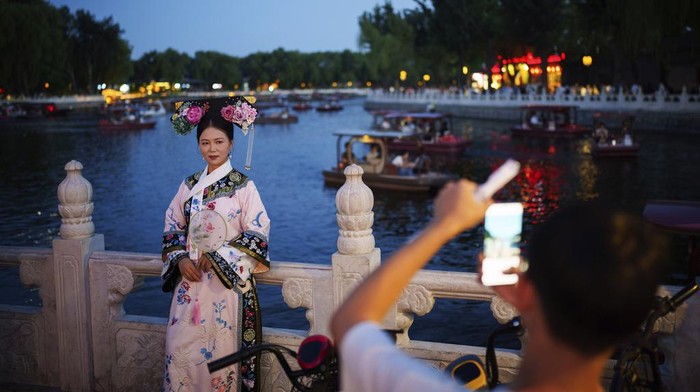 Istana Kekaisaran Beijing Diramaikan Pengunjung Berkostum Dinasti Qing Chinese girls dressed in Qing Dynasty attire take pictures outside the Drum Tower at Gulou East Street in Beijing, China, Tuesday, July 16, 2024. (AP Photo/Vincent Thian)