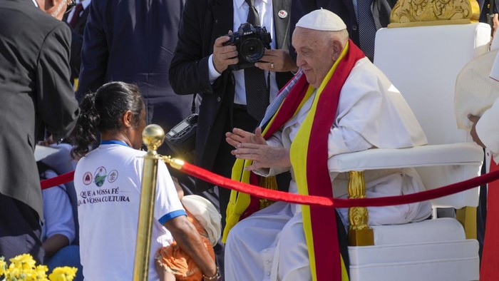 Momen Paus Fransiskus Pimpin Misa Nazar di Timor Leste Archbishop of Dili Cardinal Virgilio do Carmo da Silva, right, protects Pope Francis, wearing an East Timor traditional scarf, from the sun with an umbrella with the colors of the Vatican flag as he arrives to preside over a votive mass of the Blessed Virgin Mary Queen in Tasitolu, some 8 kilometers west of Dili, East Timor, Tuesday, Sept. 10, 2024. Pope Francis presides over a mass in a seaside park on the same field where St. John Paul II celebrated a historic liturgy during East Timor's fight for independence from Indonesian rule. (AP Photo/Gregorio Borgia)