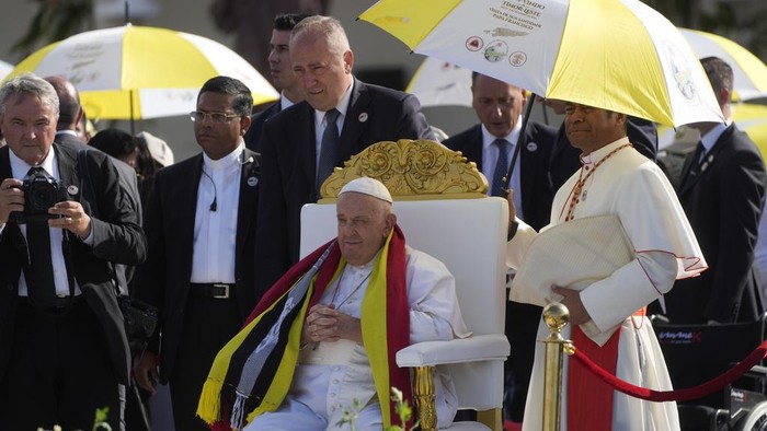 Momen Paus Fransiskus Pimpin Misa Nazar di Timor Leste Archbishop of Dili Cardinal Virgilio do Carmo da Silva, right, protects Pope Francis, wearing an East Timor traditional scarf, from the sun with an umbrella with the colors of the Vatican flag as he arrives to preside over a votive mass of the Blessed Virgin Mary Queen in Tasitolu, some 8 kilometers west of Dili, East Timor, Tuesday, Sept. 10, 2024. Pope Francis presides over a mass in a seaside park on the same field where St. John Paul II celebrated a historic liturgy during East Timor's fight for independence from Indonesian rule. (AP Photo/Gregorio Borgia)