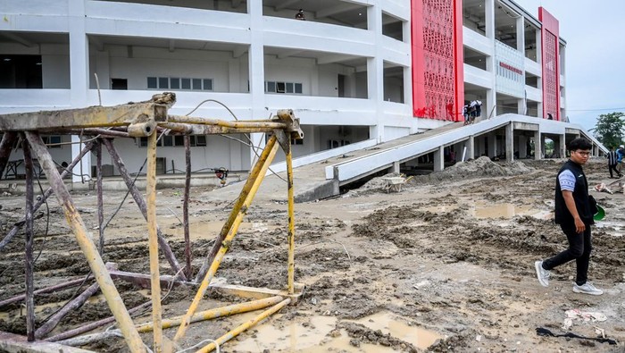 Pengunjung PON XXI Aceh-Sumut melewati jalan berlumpur di GOR Bola Voli Indoor Sumut Sport Center, Kabupaten Deli Serdang, Sumatera Utara, Selasa (10/9/2024). Pertandingan voli indoor yang semula dijadwalkan Selasa (10/9) diundur menjadi Rabu (11/9) karena GOR belum siap dan akses jalan berlumpur. ANTARA FOTO/Rivan Awal Lingga/nz