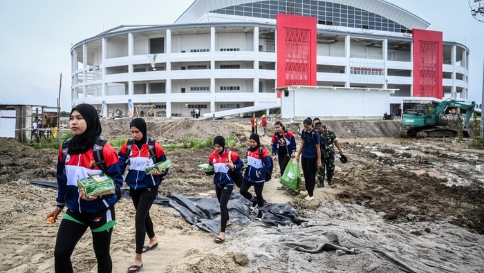 Pengunjung PON XXI Aceh-Sumut melewati jalan berlumpur di GOR Bola Voli Indoor Sumut Sport Center, Kabupaten Deli Serdang, Sumatera Utara, Selasa (10/9/2024). Pertandingan voli indoor yang semula dijadwalkan Selasa (10/9) diundur menjadi Rabu (11/9) karena GOR belum siap dan akses jalan berlumpur. ANTARA FOTO/Rivan Awal Lingga/nz