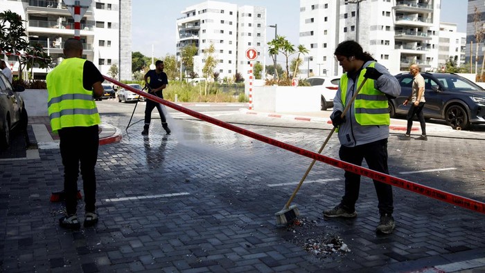 People sweep the ground, after projectiles attack towards Israel from Lebanon, amid cross-border hostilities between Hezbollah and Israeli forces, in Nahariya, northern Israel September 9, 2024. REUTERS/Shir Torem