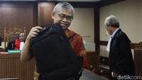 Abdul Hadi meninggalkan ruang sidang dengan menenteng tas hitam. Dia juga sempat melempar senyuman.  