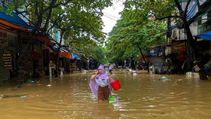 A woman holds a boy as she wades through a flooded street following the impact of Typhoon Yagi, in Thai Nguyen City, Vietnam, September 11, 2024. REUTERS/Thinh Nguyen