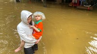 Seorang wanita menggendong anak laki-laki saat berjalan melalui jalan yang tergenang banjir setelah dampak Topan Yagi di Kota Thai Nguyen, Vietnam.  