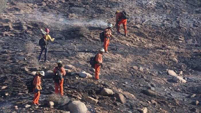 Kebakaran Hebat Hanguskan Hutan di California An emergency crew works on hotspots on a charred hillside, burned by the Bridge Fire, in Angeles National Forest, California, U.S. September 11, 2024. REUTERS/Mario Anzuoni