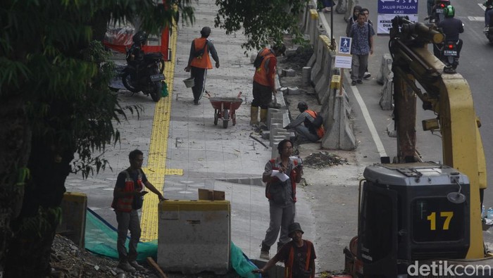 Melihat Progres Proyek Jalur Pedestrian Rasuna Said Jaksel Para pejalan kaki melintas di samping proyek jalur pedestrian di Jl Rasuna Said, Jakarta, Kamis (12/9/2024). Sebagian mulai terlihat hasilnya, sebagian lagi masih menyisakan pekerjaan karena kendala teknis seperti jaringan serat kabel bawah tanah yang membuat pekerjaan berjalan lebih lambat.
