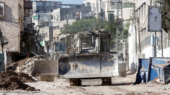 Members of the Palestine Red Crescent Society drive next to an Israeli military vehicle during an Israeli raid in Tulkarm, in the Israeli-occupied West Bank, September 12, 2024. REUTERS/Mohamad Torokman