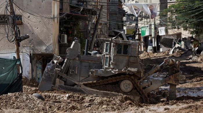 Penampakan Jalan-jalan di Tulkarm Hancur Usai Dibuldoser Israel Members of the Palestine Red Crescent Society drive next to an Israeli military vehicle during an Israeli raid in Tulkarm, in the Israeli-occupied West Bank, September 12, 2024. REUTERS/Mohamad Torokman