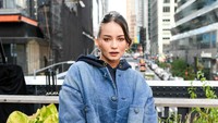 Enzy Storia mengenakan tank top hitam dengan luaran berupa jaket oversized berbahan denim, serta rok mini kulit. Padanan busananya memberi kesan bold, edgy dan androgini. (Foto: dok. Coach)
