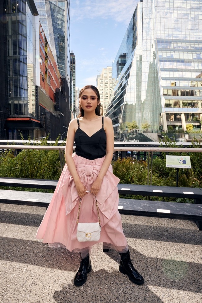 Syifa Hadju memadukan gaya edgy dan feminin dengan atasan hitam minimalis yang dipadankan rok pink beraksen pita besar. Tampilannya bold dengan sentuhan girly nan manis. Foto: dok. Coach