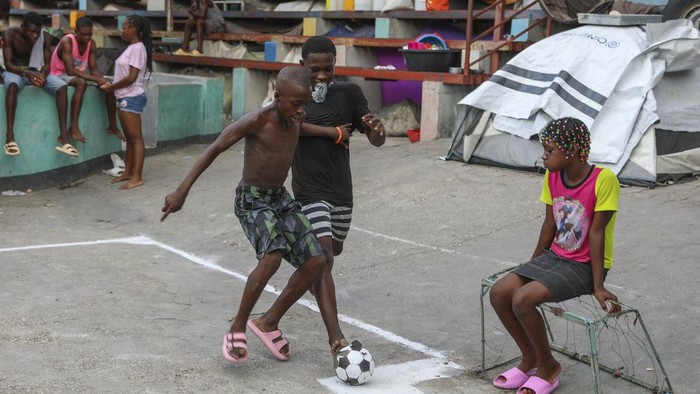Tawa Anak-anak Haiti Ditengah Kekerasan Geng Children play soccer at a gym converted into a makeshift shelter for people displaced by gang violence in Port-au-Prince, Haiti, Wednesday, Sept. 11, 2024. (AP Photo/Odelyn Joseph)