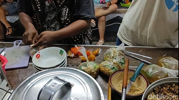 Tutung penjual mi ayam yang berpenampilan punk saat melayani pembeli di Alun-alun Purwokerto, Kamis (12/9/2024) malam.