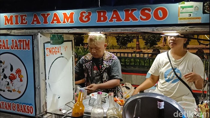 Tutung penjual mi ayam yang berpenampilan punk saat melayani pembeli di Alun-alun Purwokerto, Kamis (12/9/2024) malam.