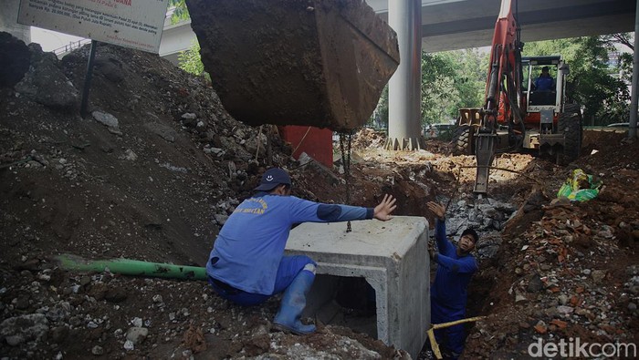 Sejumlah petugas memasang beton drainase ke dalam lubang di Kebayoran Lama, Jakarta Selatan, Jumat (13/9/2024).