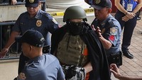 Apollo dan empat terdakwa lainnya mengenakan baju tahanan berwarna oranye dengan tangan diborgol ketika tiba di pengadilan. Dia juga terlihat mengenakan helm dan tompi antipeluru sambil didampingi oleh petugas kepolisian.