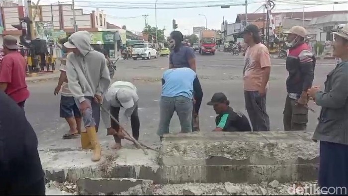 Warga membongkar beton pembatas jalan di simpang tiga Pejagan, Brebes, Jumat (13/9/2024).