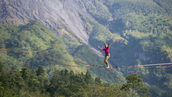 Wisatawan mancanegara berjalan di atas tali saat melakukan olahraga highline di lereng Gunung Merapi, Kalitalang, Balerante, Kemalang, Klaten, Jawa Tengah, Minggu (15/9/2024). Lokasi tebing pada lereng Gunung Merapi yang tinggi serta pemandangan yang indah menambah daya tarik dan tantangan untuk para pegiat melakukan olahraga ekstrem tersebut. ANTARA FOTO/Aloysius Jarot Nugroho/YU