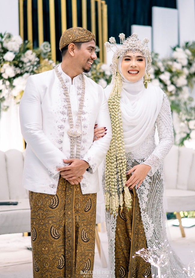 Fitri Tropica dan suami pun kembali bergaya bak pasangan pengantin. Keduanya kompak mengenakan busana pengantin adat Sunda berwarna putih. Foto: Instagram/@fitrop
