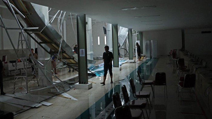Pekerja berjalan di dekat puing talang air yang ambruk di venue lapangan tembak indoor 10 meter PON XXI Aceh-Sumut 2024 di Lapangan Tembak Rindam IM Mata Ie, Aceh Besar, Aceh, Selasa (17/9/2024). Talang air tersebut ambruk akibat tidak mampu menahan beban air saat hujan deras mengguyur daerah itu. ANTARA FOTO/Arnas Padda/aww.