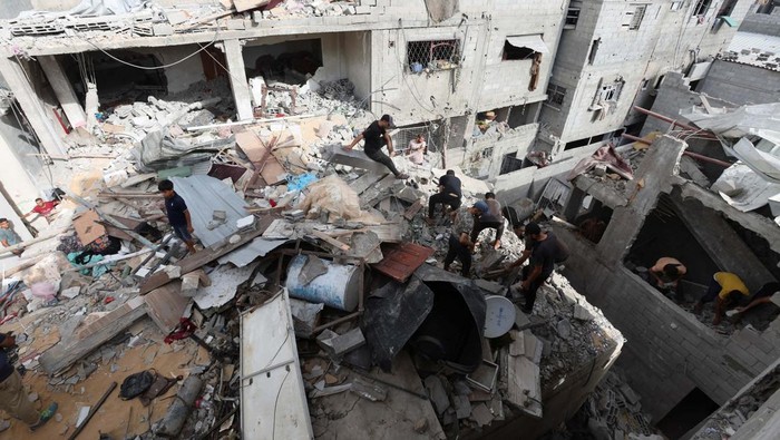 Palestinians, seen through a torn tent, ride a motorized vehicle past the rubble, amid the Israel-Hamas conflict, in Khan Younis, in the southern Gaza Strip, September 16, 2024. REUTERS/Mohammed Salem     TPX IMAGES OF THE DAY