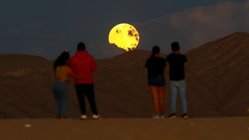 Orang-orang menyaksikan terbitnya bulan purnama menjelang gerhana bulan di Samalayuca Dunes di pinggiran Ciudad Juarez, Meksiko, 17 September 2024. REUTERS/Jose Luis Gonzalez