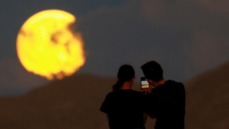 Orang-orang menyaksikan terbitnya bulan purnama menjelang gerhana bulan di Samalayuca Dunes di pinggiran Ciudad Juarez, Meksiko, 17 September 2024. REUTERS/Jose Luis Gonzalez