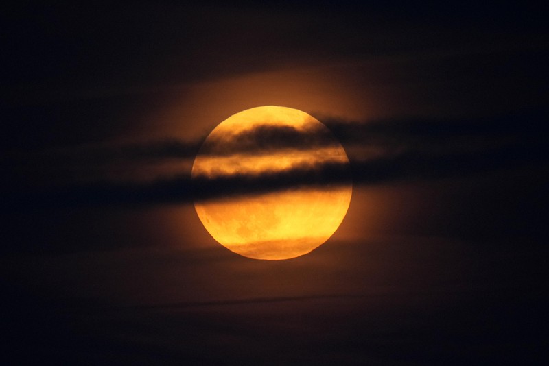 A supermoon rises behind clouds over Larnaca international airport in the eastern Mediterranean island of Cyprus, on Tuesday, Sept. 17, 2024. (AP Photo/Petros Karadjias)