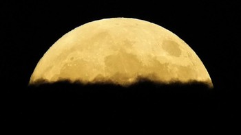 Supermoon muncul di balik awan di atas bandara internasional Larnaca di pulau Mediterania timur Siprus, Selasa (17/9). Foto: AP/Petros Karadjias