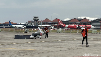Pekerja menyiapkan model pesawat Vela Alpha, taksi terbang buatan Bandung. Latar belakang terlihat pesawat-pesawat komersial yang tengah parkir di Bandara I Gusti Ngurah Rai. Pameran ini tidak akan mengganggu penerbangan ke Bali. Foto: Dadan Kuswaraharja